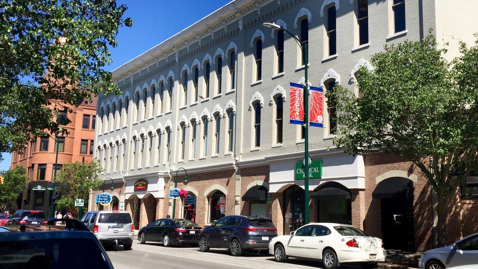 Historic storefronts with arched windows, street trees, and parked cars along Front Street in downtown Traverse City